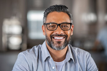 A middle-eastern looking man wearing glasses posing for a picture