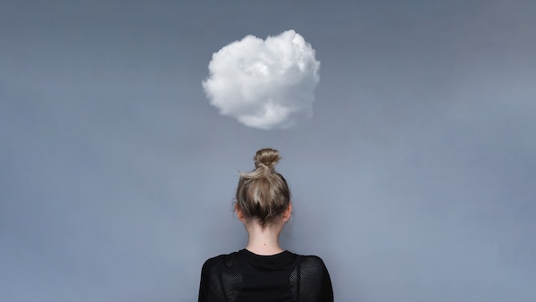 A female facing a wall with a white cloud above her head